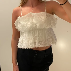 Vit fluffig linnetopp med volang - Supersöt vit linnetopp med fluffig textur och volangdetaljer. Toppen har tunna axelband som går att ta av för en axelbandslös look. Den är croppad och har en luftig, lätt känsla – perfekt för varma dagar eller när du vill sticka ut lite extra.🪽💕