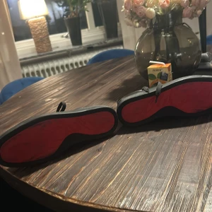 Svarta Loubs - Snygga svarta sneakers från Christian Louboutin i skinn med klassisk röd sula. Skorna har rund tå, svarta skosnören och diskret logga på sidan. Perfekta för dig som vill ha en stilren men ändå lyxig look med en ikonisk touch.