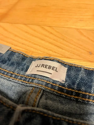Blå jeans från JJ Rebel regular fit - Säljer ett par klassiska blå jeans från JJ Rebel i regular fit. Jeansen har raka ben. Jeansen är sprillans nya och har inte använts en enda gång vilket gör att de fortfarande har kvar storlekslappen. Om du är nyfiken eller har frågor så svarar jag alltid snabbt! Frakt sker inom 24h!💨📦