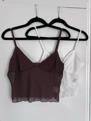 2 linnetoppar i mesh brun & vit, storlek M & S - Säljer två linnetoppar i mesh, en chokladbrun och en vit. Båda har tunna axelband, v-ringad front och vågig kant nedtill. Den vita är omlott. - Köper du innan kl 16:00 kan jag skicka samma dag!