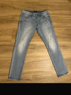 Ljusblå skinny jeans - Säljer ett par ljusblå skinny jeans med klassisk femficksdesign och snygga slitningar på framsidan. Jeansen har normal midja och smal passform hela vägen ner. Perfekta till sneakers och hoodie för en chill look.storlek: 33/32! 