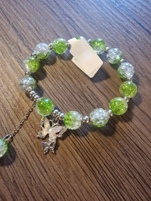 Armband butterfly - Elastiskt pärlarmband med silverfärgade detaljer och en fjärilsberlock.Stretch. Armbandet har pärlor i gröna nyanser. En extra pärla hänger som en berlock.