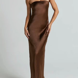 Balklänning - Snygg brun axelbandslös långklänning i glansigt satintyg, perfekt till balen!😍Klänningen har en smickrande figurnära passform och öppen rygg med dekorativa knappar upptill. Perfekt för dig som vill ha en elegant och trendig look. Aldrig använd, nypris 1300 kr!