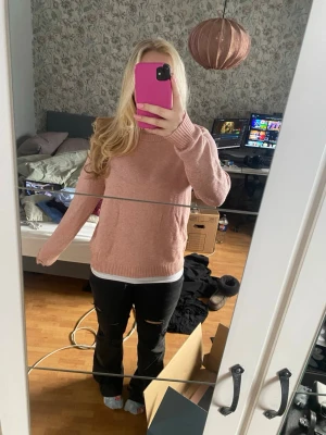 Ljusrosa stickad tröja från Vila - Mysig ljusrosa stickad tröja från Vila i storlek M. Tröjan har rund hals, ribbade muddar och lång ärm. Perfekt för lager på lager och enkel att matcha med jeans eller kjol.