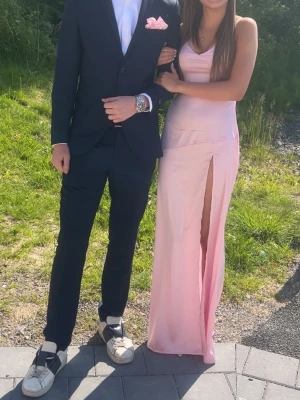 Söt silkes balklänning  - Säljer en elegant ljusrosa silkes klänning med v-ringad urringning och smala axelband. Klänningen har en slits på ena sidan. Materialet är glansigt och faller fint längs kroppen, perfekt till student eller bal. Passar xs-s då man väljer storlek och hur hårt den skall sitta baktill. Kolla alla bilder på detaljer!