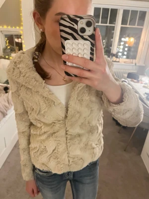 Beige pälsjacka🤍 - Supermjuk och fluffig pälsjacka från Vero Moda i beige färg. Jackan har vågigt mönster i pälsen, huva och knäppning framtill. Perfekt för dig som vill ha en cozy och trendig look. Passar till jeans eller kjol och är riktigt skön nu till våren🤍