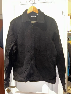 Svart overshirt från Weekday - Säljer en svart overshirt från Weekday i manchestertyg. Jackan har klassisk krage, bröstficka och dragkedja framtill. Perfekt för dig som gillar en enkel och clean look. Passar till det mesta och är riktigt skön att bära.