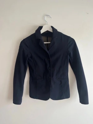 Marinblå kavaj från Cavalleria Toscana - Snygg marinblå kavaj från Cavalleria Toscana , tre knappar framtill och diskreta fickor med dragkedja. Kavajen har en figurnära passform och ett mönstrat innerfoder. Har blivit lite nopprigt på framsidan, se bild:)