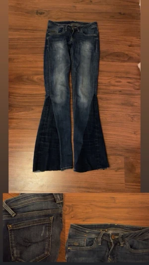 Mörkblå bootcut jeans med snörning - Unika mörkblå jeans med breda bootcut-ben och snörning i midjan. Jeansen har slitningar framtill och klassiska fickor både fram och bak. Materialet är robust denim som ger en cool vintagekänsla.