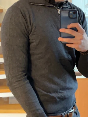 Mörkgrå half zip tröja Jack & Jones - Säljer en mörkgrå långärmad tröja från Jack & Jones med half zip-dragkedja vid halsen. Tröjan har en slim passform och är tillverkad i mjuk bomullsmix, perfekt för lager på lager under kyliga dagar.