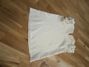 Vit blus med volangärmar - Säljer en söt vit blus med volangdetaljer på ärmarna. Blusen har rak passform och är ärmlös med breda axelpartier som pryds av dubbla volanger. Perfekt för dig som gillar en feminin och stilren look.