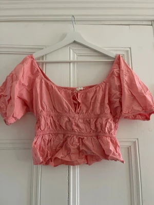 Rosa blus med puffärm och knyt - Supersöt korallrosa blus med puffärmar och smockdetaljer i midjan. Färgen är OTROLIG!! Tveka inte på att höra av dig om du har frågor❤️