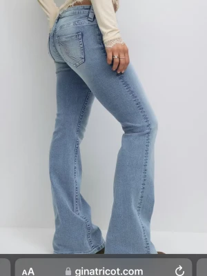 Ljusblå bootcut jeans från Gina Tricot - Säljer ett par ljusblå jeans med bootcut-modell från Gina Tricot. Jeansen har klassisk femficksdesign, låg midja och är tillverkade i mjukt denimtyg med lite stretch. Perfekta för dig som gillar retrovibbar och vill ha en snygg siluett.