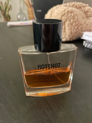 Hotshot Eau de Parfum - Hotshot Eau de Parfum från Linn Ahlborg x Nordicfeel. En trendig parfym som sticker ut och passar dig som vill ha något unikt i din samling. Perfekt för dig som gillar att testa nya dofter och vill ha en modern vibe. Säljs inte längre 