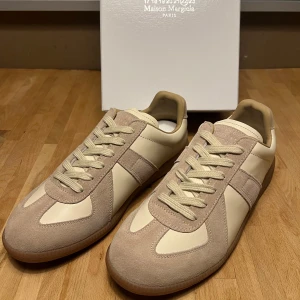 Maison Margiela sneakers beige mocka - Maison Margiela sneakers i beige och ljusbrun färg med ovandel i mjuk mocka och släta skinnpaneler. Klassisk låg modell med rund tå, platt sula och snörning. Snygg minimalistisk design som passar till allt. 