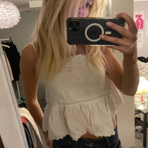 Vit broderad topp med volang - Superfin vit topp med broderade detaljer och volang nertill. 