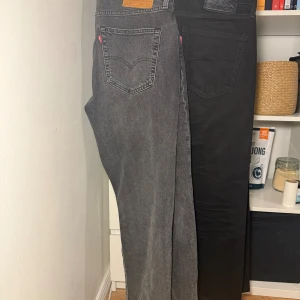 Levi's 514 jeans i grått och svart - Två par Levi's 514 jeans, ett par i tvättad grå och ett par i svart. Klassisk femficksmodell med raka ben och normal passform. Snygga detaljer med Levi's-lappar bak i läder och svart. Perfekta jeans för dig som gillar stilren och enkel look. Aldrig använda