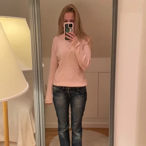 Ljusrosa stickad tröja - Säljer en ljusrosa stickad tröja med kabelstickat mönster. Tröjan har rund halsringning och långa ärmar, sitter snyggt med en normal passform. Perfekt att slänga på sig när det är lite kyligare ute.