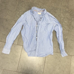 Ljusblå skjorta Holly & Whyte 170 - Klassisk ljusblå skjorta från Holly & Whyte by Lindex. Skjortan har lång ärm, knappar framtill och en bröstficka. Tillverkad i mjuk bomull och passar perfekt till en avslappnad men ändå stilren look.