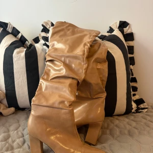 Beiga stövlar med klack och spetsig tå - Säljer ett par snygga beiga stövlar med hög klack och spetsig tå. Skorna har en rynkad design på skaftet och dragkedja på insidan för enkel påtagning. Strl 38. Mycket bra skick. 