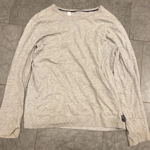 Ljusgrå långärmad tröja från H&M - En basic ljusgrå långärmad tröja från H&M i mjuk bomullsmix. Tröjan har rund halsringning och ribbade muddar vid ärmslut och nederkant. Perfekt att slänga på sig till jeans eller joggers.