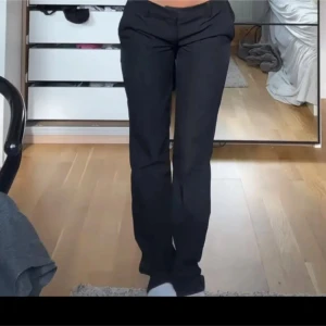 Svarta kostymbyxor med raka ben - Snygga svarta kostymbyxor med klassisk rak passform och diskret midja. Perfekta för en clean och stilren look. Byxorna har enkel knäppning framtill och är tillverkade i ett mjukt tyg som ger en dressad känsla. Kostymbyxorna är ifrån bikbok i den populära modellen Vera