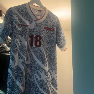 Corteiz fotbollströja  M - Säljer en unik fotbollströja från C-Star i storlek medium. Tröjan är blå och vit med ett randigt, abstrakt mönster och stora vita stjärnor. Nummer 18 i rött på bröstet, vita muddar med röda detaljer och V-ringad krage. Perfekt för dig som gillar retrostil och coola prints.