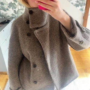 Arket kappa hög krage - Säljer min jättefina ullkappa från arket x manteco. Beige/brun/grå färg, denna modell görs ej längre. Den är i super skick och inga skavanker. Ytterlagret är 100% ull. Storlek S. Se tvättlapp
