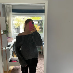 Grå offshoulder stickad tröja - Mysig grå stickad tröja med bred ribbad kant och offshoulder-modell. kommer inte längre till användning. eftersom att den tidigare varit använd är den lite luddig men ingenting man lägger märke till!