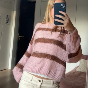 Stickad tröja från ASOS Design - Supermysig mjuk stickad tröja från ASOS Design i ljusrosa med breda bruna ränder. Tröjan har en loose fit, ribbade muddar och rund hals. Snygg till både jeans och kjol!