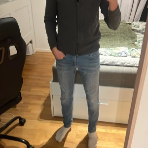Replay ljusblå slim jeans - Säljer ett par ljusblå jeans från Replay med klassisk femficksdesign och snygga slitningar. Jeansen har slim passform, raka ben och normal midja. Materialet är mjukt jeans-tyg med stretch för extra komfort. Perfekta för dig som gillar en clean och modern look. Nytt skick! 
