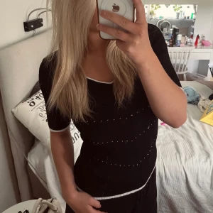 Svart ribbad topp med vita detaljer - Snygg svart ribbad topp med vita kontrastsömmar och små prickar i rader över bröstet och midjan. Söt topp som är enkel att styla! Toppen passar mig som vanligtvis bär S/M i toppar🖤🖤