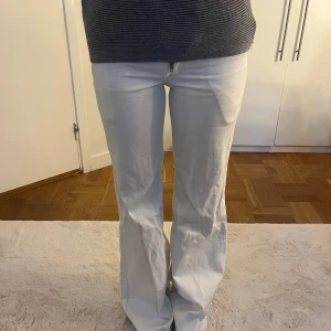 Vita bootcut Wrangler jeans - Säljer ett par vita jeans från Wrangler med bootcut-modell. Byxorna har klassisk femficksdesign, bälteshällor och dragkedja med knapp framtill. Snyggt raka ben som blir vidare nertill och passar perfekt till sneakers eller boots.