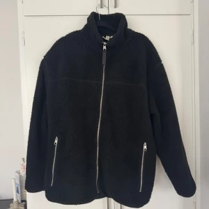 Svart teddyjacka med dragkedja - Mysig svart teddyjacka med hög krage och hel dragkedja framtill. Jackan har två fickor med dragkedja. Från Hm storlek M, pris kan diskuteras 