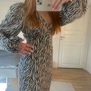 Klänning - Säljer denna långärmade klänning i zebra mönster. Mycket bra skick då den bara användts en gång! Pris går såklart att diskutera