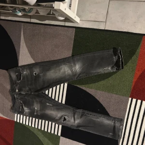 Svarta slitna jeans från Dsquared2 - Svarta jeans från Dsquared2 med coola slitningar och hål på flera ställen. Jeansen har en smal passform och klassisk femficksdesign. Perfekta för dig som gillar en edgy streetstil. Materialet är jeans i bomull.