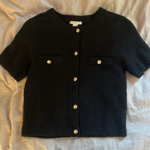 Svart kofta med guldknappar Gina Tricot - Kortärmad svart kofta från Gina Tricot med snygga guldknappar framtill, använd två gånger men är lite tussig men det går enkelt att få bort med en roller, kommer inte ihåg va jag köpte den för men säljer den för ungefär 250kr priset går att diskutera🥰🥰