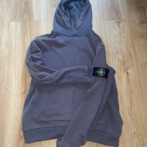 Brun hoodie från Stone Island - Säljer en brun hoodie från Stone Island med loggan på armen. Skicket är 9/10. Inga hål eller skador men den är använd ett par gånger. 