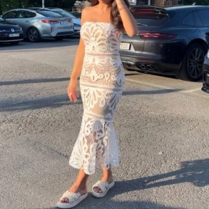 Vit spetsklänning med blommigt mönster - Säljer en superfin långklänning i vit spets med blommigt mönster. Klänningen är axelbandslös och har en figurnära passform med volangdetalj nedtill. Perfekt för sommarens alla tillfällen när du vill känna dig extra snygg och unik.