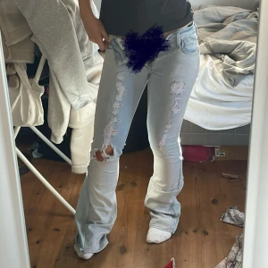 Ljusblå slitna bootcut jeans - Säljer dessa skit snygga jeans då de tyvärr är försmå för mig. De är lågmidjade och utsydda till bootcut och har slitningar på benen. Midjemått 34 cm tvärs över midjan och innerbenslängd 80 cm. Säljer även fler jeans i min profil💕