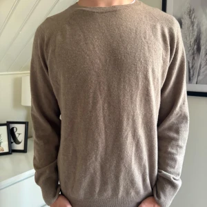 Beige kashmirtröja från Oscar Jacobson - Riktigt snygg och stilren beige tröja från Oscar Jacobson i kashmir. Tröjan har rundhalsringning och perfekt för dig som vill ha en skön tröja inför hösten. Killen på bilden är 178cm.