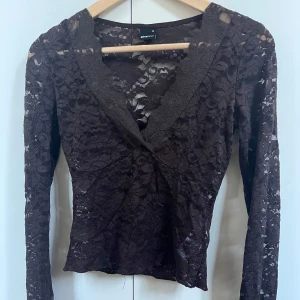 Brun spetsblus från Gina Tricot XS - Säljer en brun långärmad spetsblus från Gina Tricot i storlek XS. Blusen har v-ringning och är helt i genombruten spets med blommigt mönster. Perfekt för dig som gillar detaljer och vill ha en feminin look. Säljs pga jag inte anvönder den längre❤️