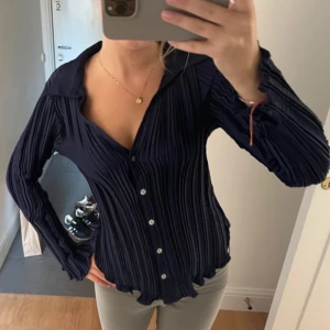 Mörkblå plisserad skjorta från MNG - Säljer en mörkblå plisserad skjorta från MNG med snygg v-ringning och klassisk krage. 