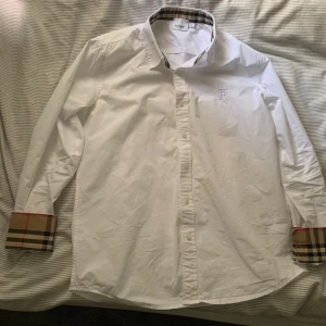 Vit Burberry skjorta med rutiga detaljer - Säljer en klassisk vit skjorta från Burberry i bomull. Kan mötas i Göteborg