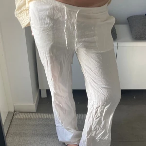 Vita linnebyxor med snörning - Säljer ett par vita linnebyxor med avslappnad passform och snörning i midjan. Byxorna har raka ben och är perfekta för varma dagar. Lätta och luftiga, tillverkade i linne för en skön känsla. Passar dig som gillar en chill och enkel stil. Är lite slitna längst ner 