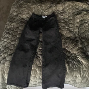 Svarta wide jeans från lager 157, stl 150 - Svarta jeans från lager 157 Boulevard Star i storlek 150. Byxorna har en bred, rak passform med klassiska fem fickor och knappgylf. Snygg minimalistisk look som passar till det mesta. Materialet är jeans och färgen är helsvart.