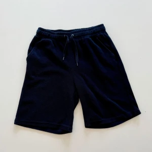 Svarta shorts med snörning - Svarta shorts med elastisk midja och snörning. Mjukt material och avslappnad passform, perfekta för varma dagar eller chill hemma. Klassisk design med fickor på sidorna.