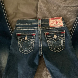 True Religion jeans med kontrastsömmar - Säljer ett par trendiga blå True Religion jeans W26 för 750kr ELLER kan byta mot ett par vicktoria Beckham jeans med kronor på fickorna. As snygg tvättning och färger. 