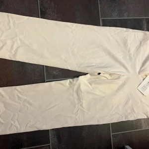 Beiga kostymbyxor från Y.A.S - Stilrena beiga kostymbyxor från Y.A.S med raka ben och hällor för bälte. Byxorna har diskreta bakfickor och är tillverkade i ett mjukt material som ger en clean look. Perfekta för dig som gillar en klassisk och fräsch stil. Helt oanvända! 