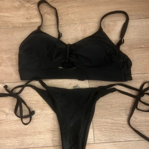Svart bikini - Svart Bikini, snören på underdelen och rosett man knyter i ryggen på överdelen💌 Överdelen är i ungefär i storlek 75D och underdelen är i storlek M💌 